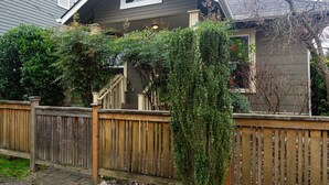 Una casa con valla de madera, un porche cubierto y un pequeño jardín.