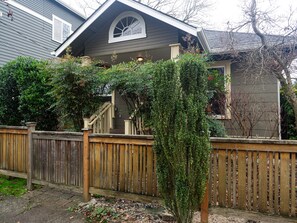 Une maison avec une clôture en bois, une véranda et un petit jardin.