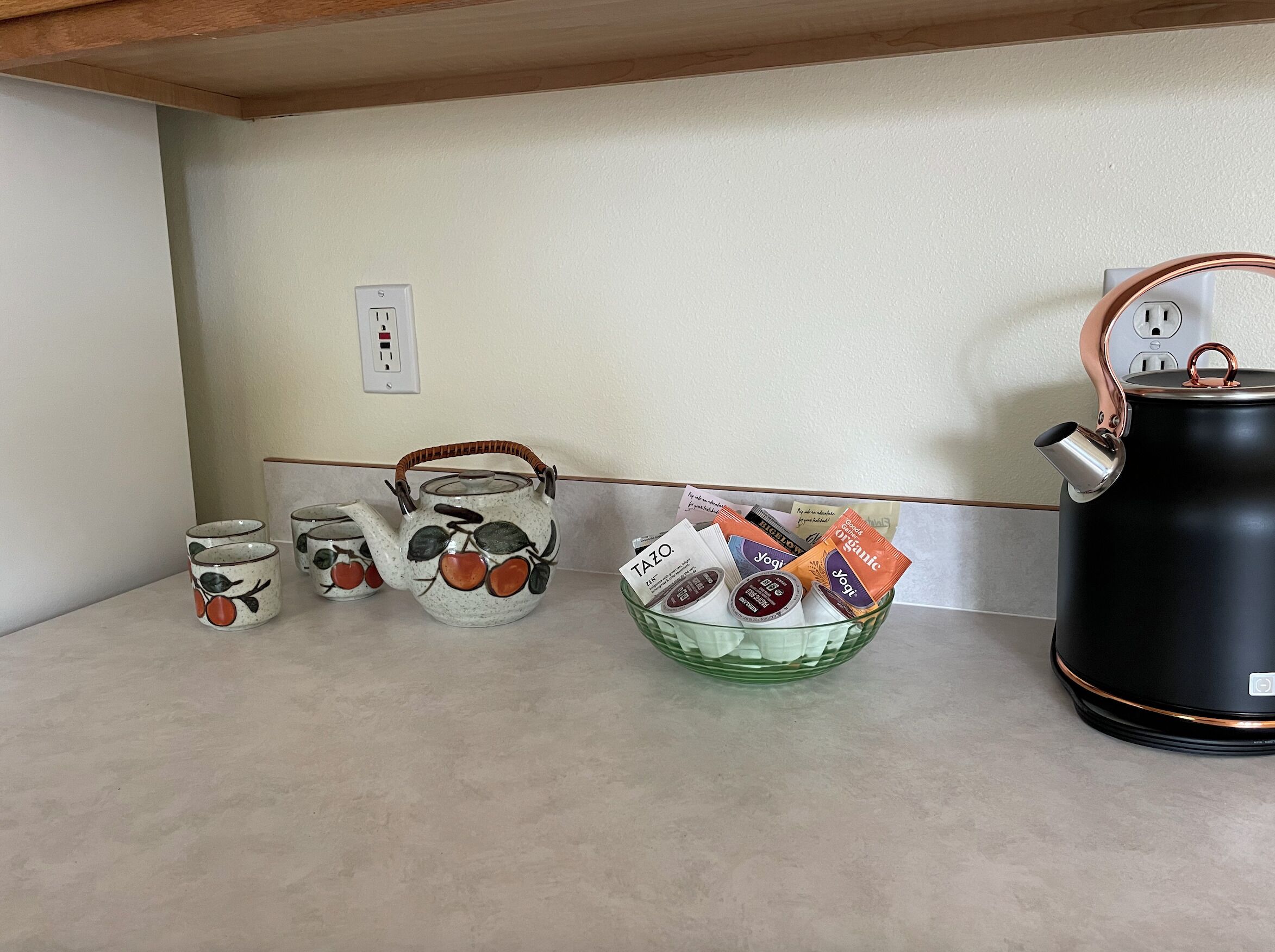A kitchen counter with a coffee maker, a kettle, and a basket of tea bags.