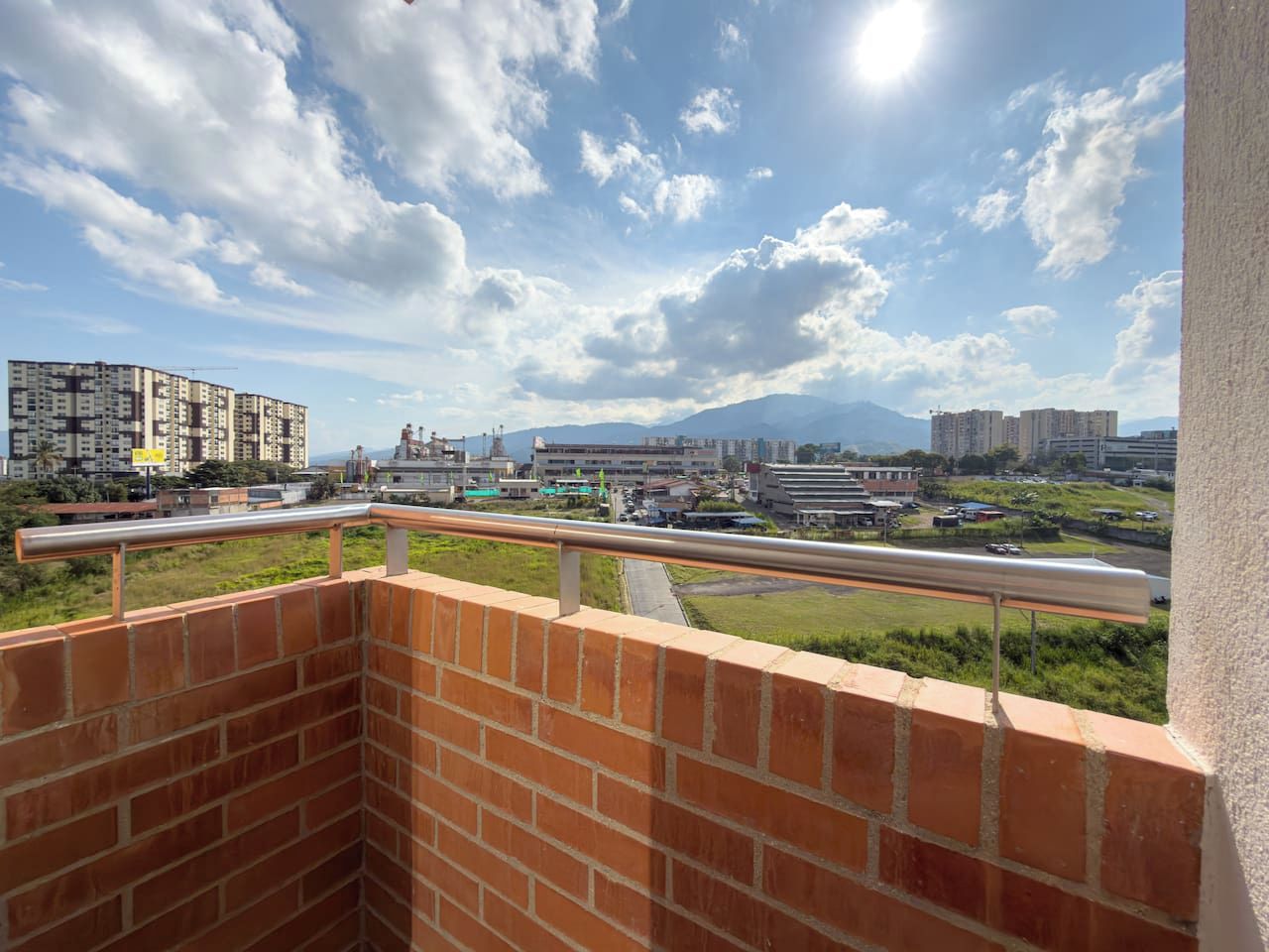 A balcony with a view of a cityscape, including buildings and a road.