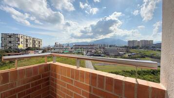 A balcony with a view of a cityscape, including buildings and a road.
