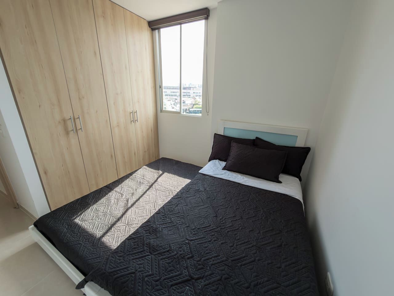 A bedroom with a bed, a window, and a wardrobe.