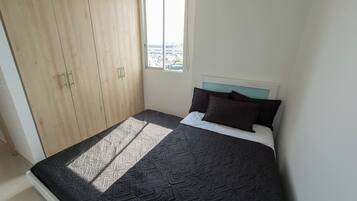 A bedroom with a bed, a window, and a wardrobe.