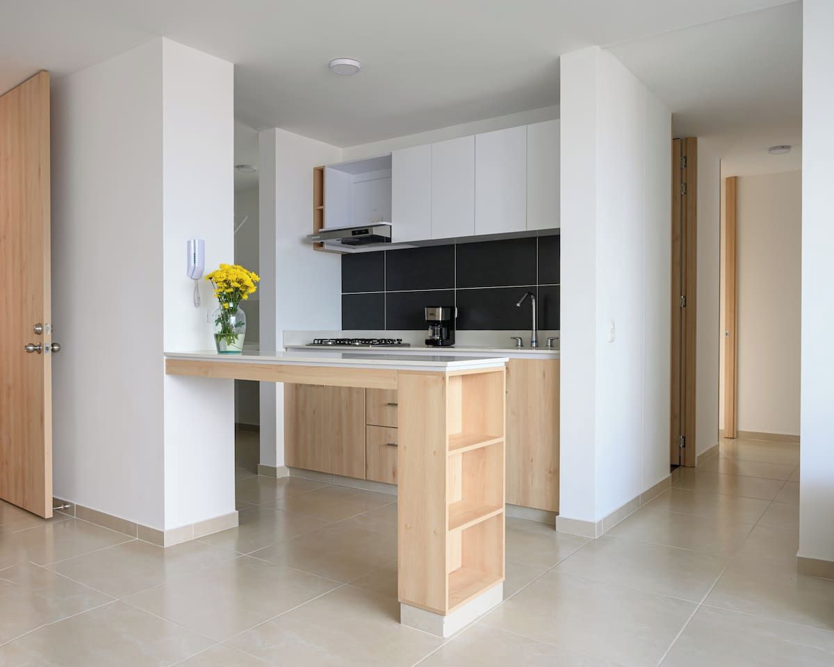Cozinha moderna com ilha central, armários brancos e cafeteira.