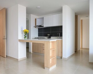 Una cocina moderna con una isla central, armarios blancos y una cafetera.