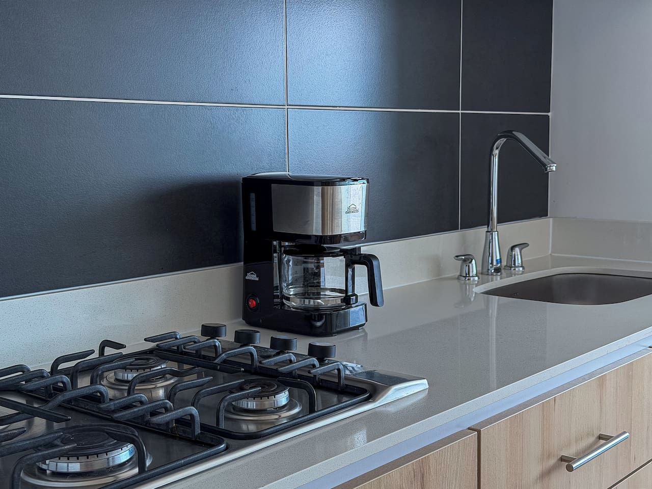 Een moderne keuken met een gasfornuis, een koffiezetapparaat en een spoelbak.