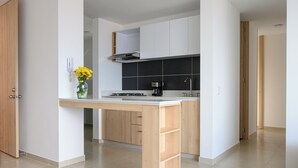 Une cuisine moderne dotée d’un îlot central, de meubles blancs et d’un pare-feu noir.