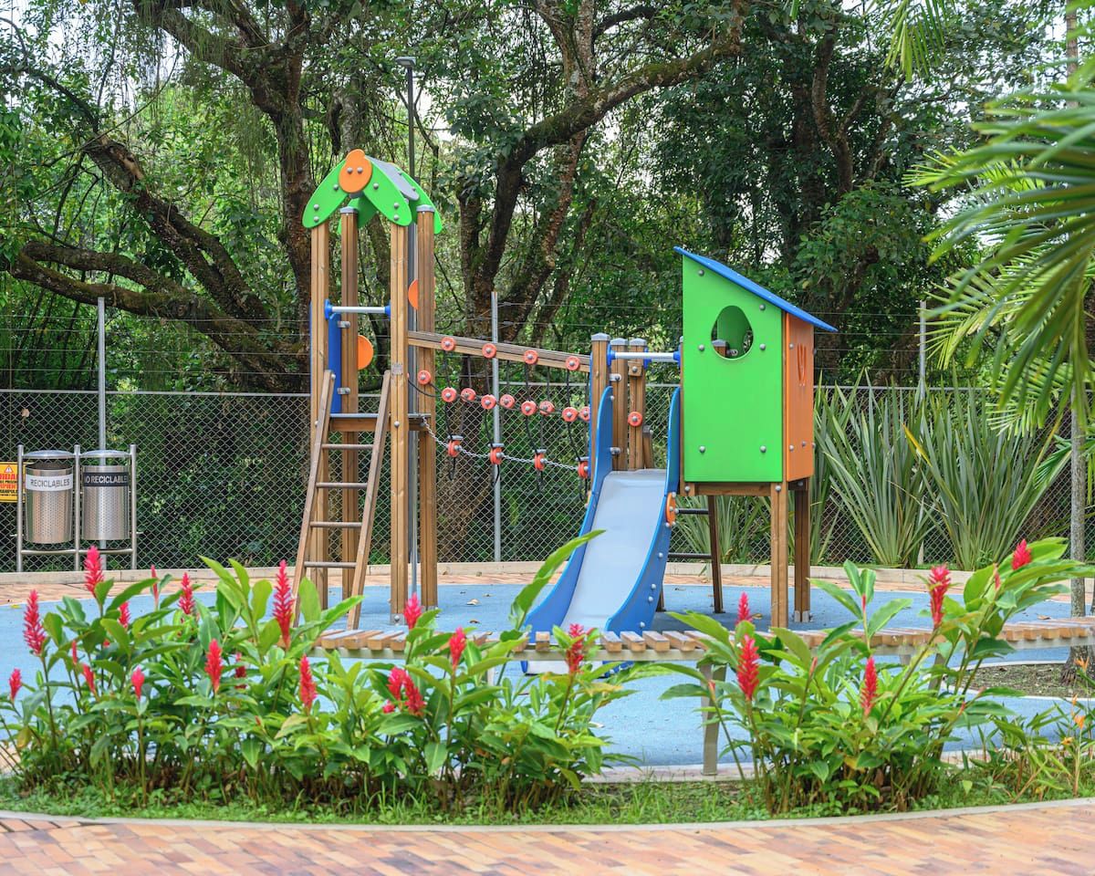 A playground with a slide, climbing structures, and a green playhouse.