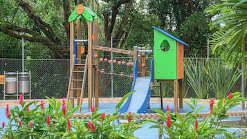 A playground with a slide, climbing structures, and a green playhouse.