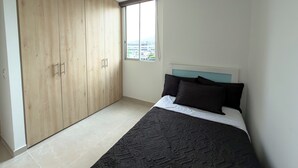 Une chambre à coucher avec un lit, une grande armoire et une fenêtre donnant sur la ville.