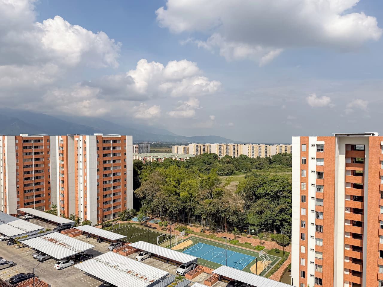 A residential complex with multiple high-rise buildings, a basketball court, and surrounding greenery.