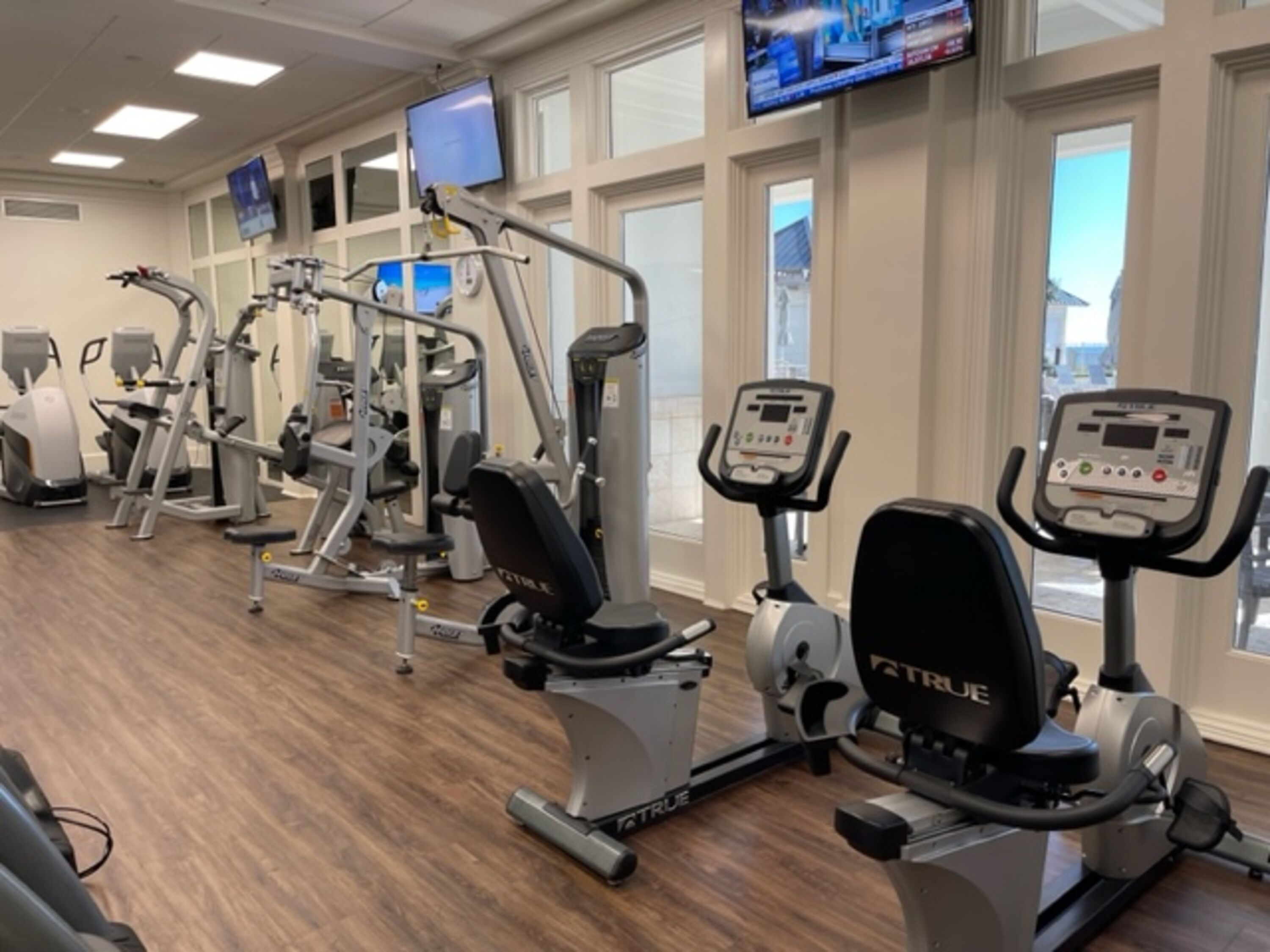 A gym with various exercise machines, including treadmills and weight machines, arranged in a row.