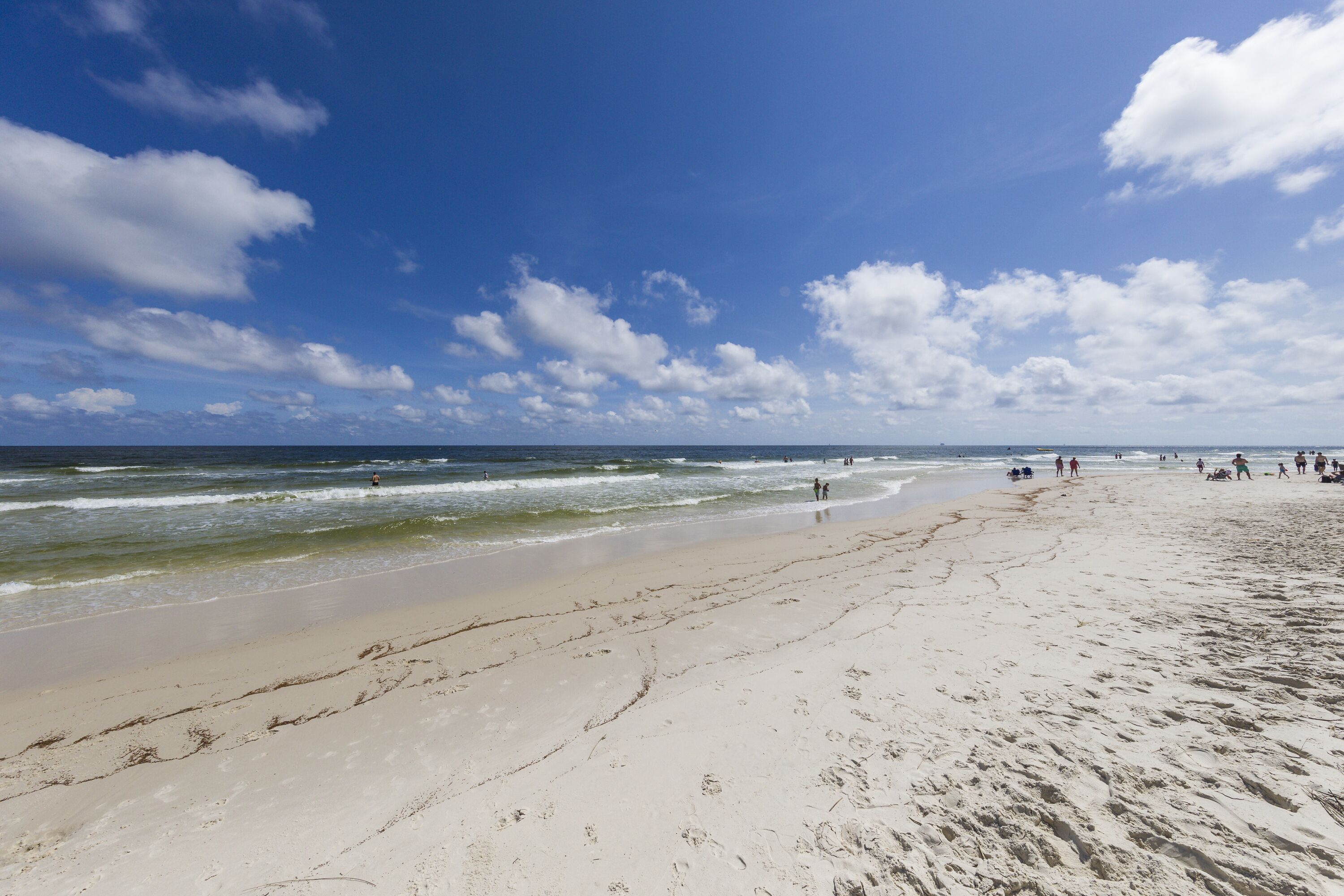 A wide sandy beach with gentle waves and a clear blue sky.