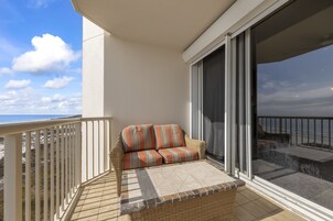 A balcony with a wicker sofa and a view of the beach.