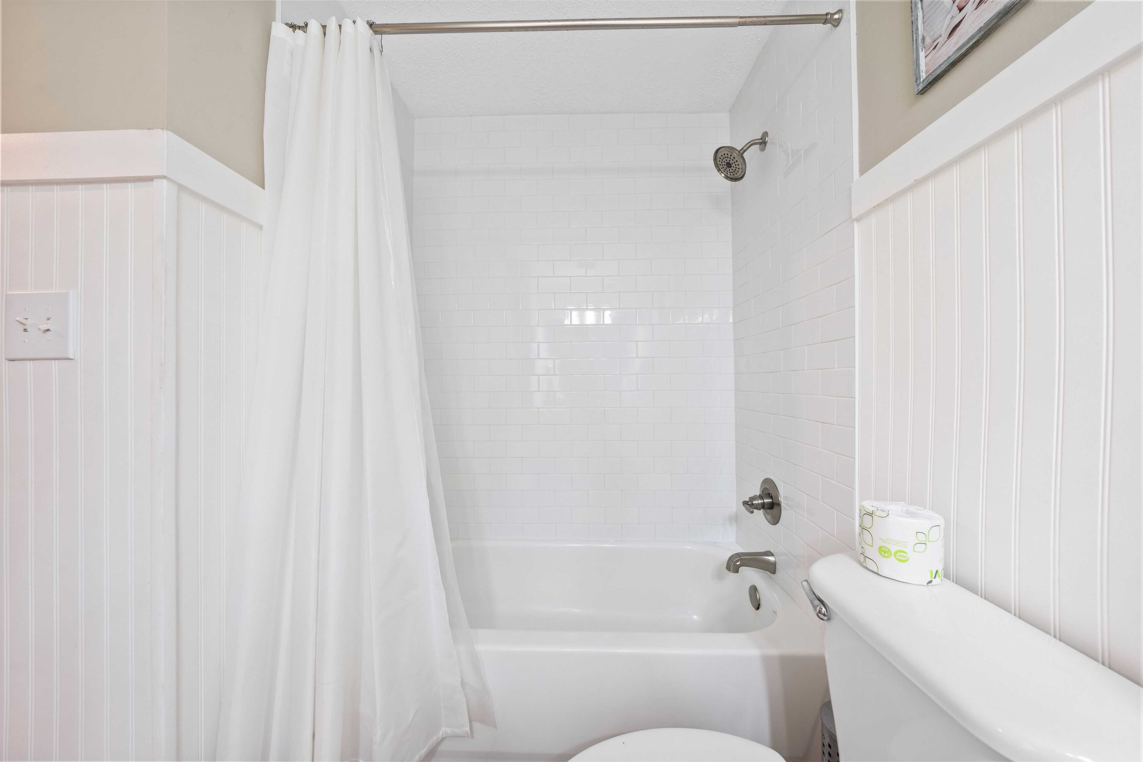 A bathroom with a shower, toilet, and a towel rack.