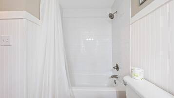 A bathroom with a shower, toilet, and a towel rack.