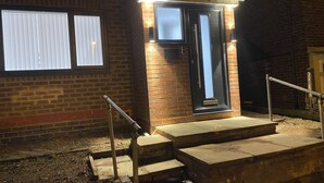 A brick building with a black door, a small window, and a metal handrail leading to the entrance. - Ready Stay (Birmingham)