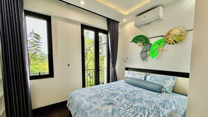 Une chambre à coucher moderne avec un grand lit, une vue sur la verdure et des éventails décoratifs accrochés au mur.