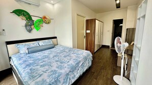 Une chambre à coucher avec un lit, un ventilateur sur pied et une armoire.