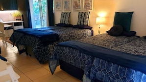 Ein Hotelzimmer mit zwei Betten, einem Schreibtisch, einem Stuhl und einer Lampe.