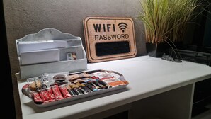 Eine Auswahl an Snacks auf einem Tablett und ein Schild mit dem Hinweis auf ein WLAN-Passwort auf einer Theke.