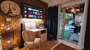 Ein modernes Wohnzimmer mit Schreibtisch, großer Uhr und Fernseher, der Streamingdienste anzeigt.