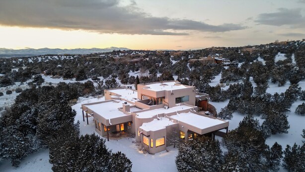 Una casa moderna de varios pisos rodeada de árboles cubiertos de nieve.