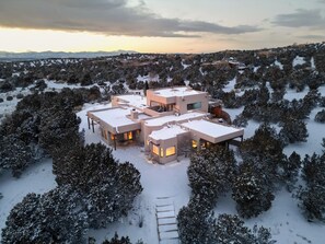 Une maison moderne à plusieurs étages, entourée d’arbres couverts de neige.