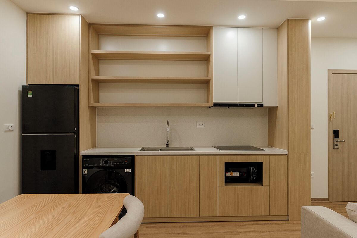 Una cucina compatta con mobili in legno, un frigorifero nero, una lavastoviglie e un lavello.
