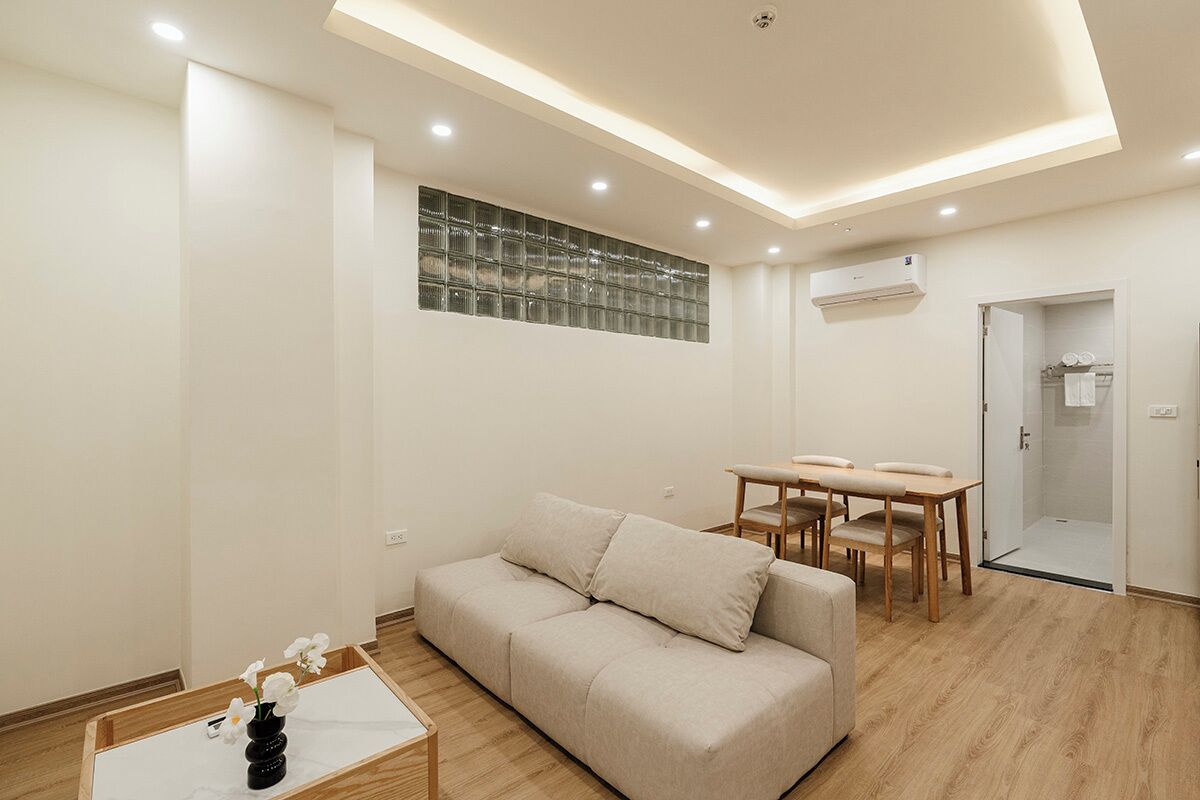 Ein modernes Wohnzimmer mit einem beigefarbenen Sofa, einem Holztisch und einem Essbereich mit Tisch und Stühlen.