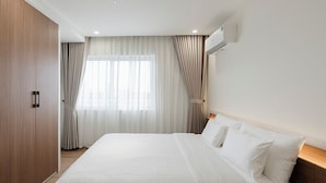 Une chambre d’hôtel avec un grand lit, une armoire et un climatiseur fixé au mur.