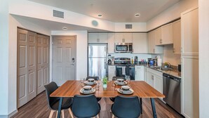 A modern kitchen with white cabinets, a microwave, a refrigerator, and a dining table set for four. - Westgate Area Balcony, Pool, Gym Parking WD (Glendale)