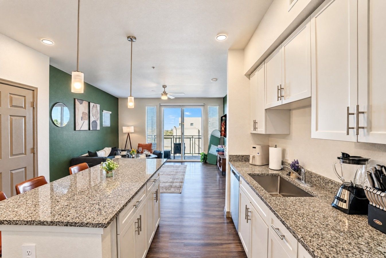 A modern kitchen with granite countertops, white cabinets, and a central island.