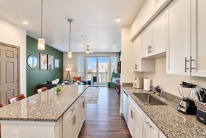 A modern kitchen with granite countertops, white cabinets, and a central island. - Modern Retreat | Stadium | Pool | Gym | W/D | PKG (Glendale)