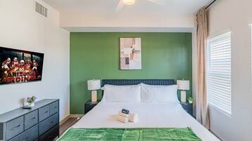 A hotel room with a bed, nightstands, a green wall, a ceiling fan, and a window with curtains.