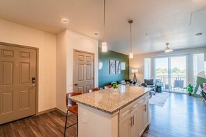 A modern kitchen with a granite countertop, wooden cabinets, and a dining area with chairs. - Westgate Near Stadium Balcony Pool Parking Gym WD (Glendale)