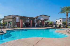Un hotel con piscina, mobiliario exterior y palmeras.