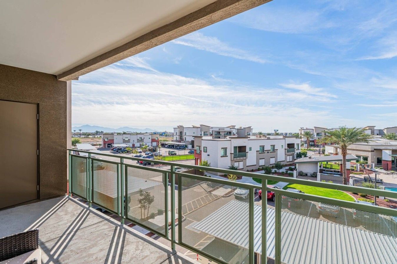 A balcony with a view of a residential area, including modern buildings and a parking lot.