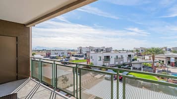 A balcony with a view of a residential area, including modern buildings and a parking lot.