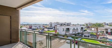 A balcony with a view of a residential area, including modern buildings and a parking lot.