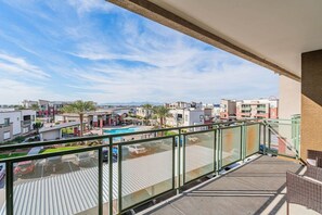 A balcony with a view of a swimming pool, adjacent buildings, and a clear sky. - Near Stadium | Pool Gym Balcony Parking WD (Glendale)