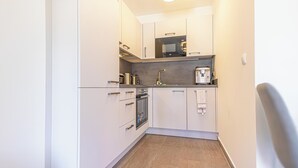 A compact kitchen with white cabinets, a microwave, a coffee machine, and a small oven. - Modern 1BR 1LR Balcony City Centers (Vienna)