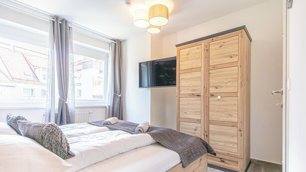 A bedroom with a bed, a wardrobe, a television, and a window with curtains. - Modern 1BR 1LR Balcony City Centers (Vienna)