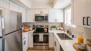 A modern kitchen with stainless steel appliances, white cabinetry, and a central island. - Near Old Town | Pool+Gym+Balcony+Parking+WiFi+WD (Scottsdale)