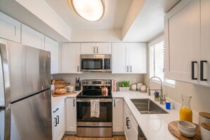 A modern kitchen with stainless steel appliances, white cabinetry, and a central island. - Near Old Town | Pool+Gym+Balcony+Parking+WiFi+WD (Scottsdale)