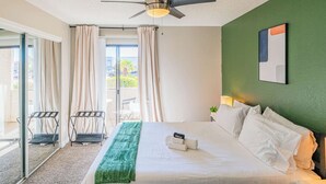 A hotel room with a bed, a ceiling fan, a green wall, and a view through the glass door. - Near Old Town | Pool+Gym+Balcony+Parking+WiFi+WD (Scottsdale)