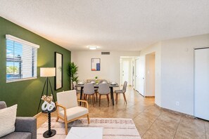 A modern living room with a dining area, a sofa, a coffee table, and a lamp. - Near Old Town | Pool+Gym+Balcony+Parking+WiFi+WD (Scottsdale)