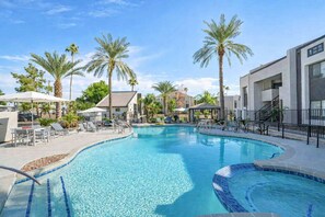 A swimming pool with lounge chairs and palm trees. - Stylish Condo: Pool, Gym, Balcony, Parking, W/D (Scottsdale)