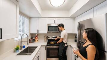 Una cocina moderna con armarios blancos, electrodomésticos de acero inoxidable y una isla central.