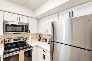 Una cocina moderna con electrodomésticos de acero inoxidable, armarios blancos y un horno empotrado.